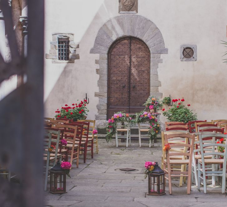 Outdoor Wedding Ceremony in Tuscany With Bright Florals And Rustic Wooden Seating