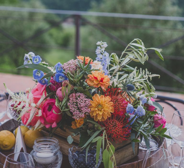 Outdoor Wedding Ceremony in Tuscany With Bright Florals And Rustic Wooden Seating