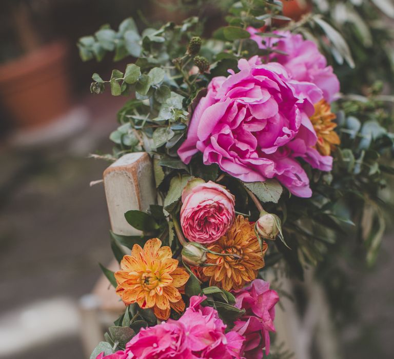 Outdoor Wedding Ceremony in Tuscany With Bright Florals And Rustic Wooden Seating