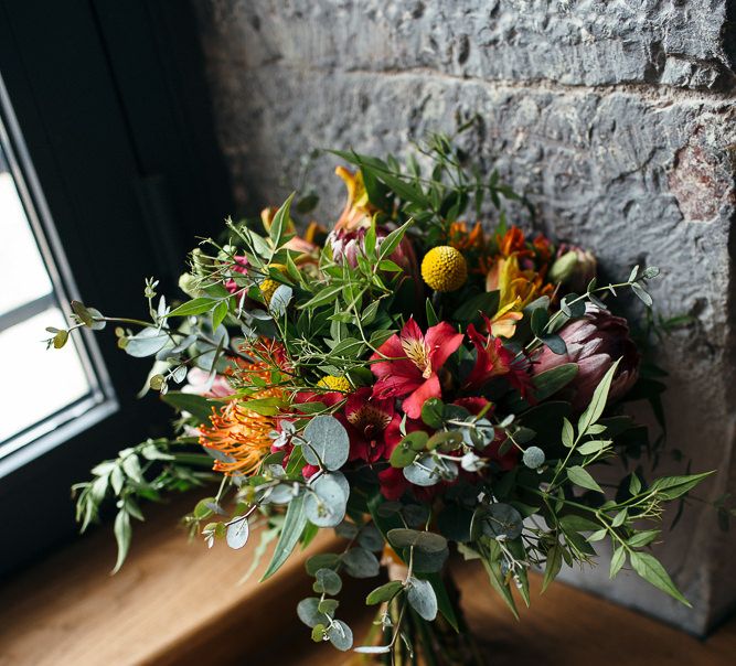 Colourful Red, Orange & Yellow Bouquet with Proteas | Relaxed Industrial Wedding at Ocean Studios, Plymouth | Freckle Photography