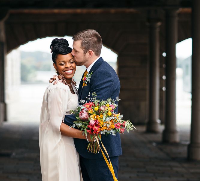 Bride in Bespoke Ailsa Monroe Jumpsuit & Cape | Groom in Next Navy Wool Suit | Relaxed Industrial Wedding at Ocean Studios, Plymouth | Freckle Photography