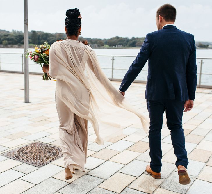 Bride in Bespoke Ailsa Monroe Jumpsuit & Cape | Groom in Next Navy Wool Suit | Relaxed Industrial Wedding at Ocean Studios, Plymouth | Freckle Photography