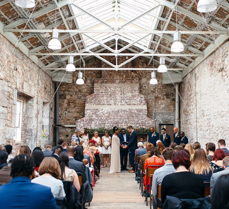 Wedding Ceremony | Bride in Bespoke Ailsa Monroe Jumpsuit & Cape | Groom in Next Navy Wool Suit | Relaxed Industrial Wedding at Ocean Studios, Plymouth | Freckle Photography