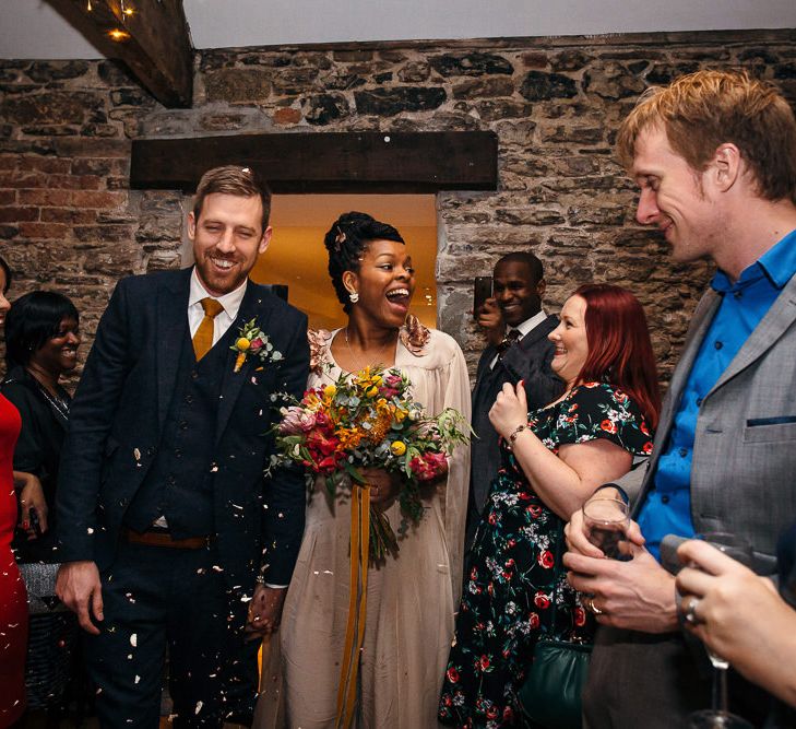 Confetti Exit | Bride in Bespoke Ailsa Monroe Jumpsuit & Cape | Groom in Next Navy Wool Suit | Relaxed Industrial Wedding at Ocean Studios, Plymouth | Freckle Photography