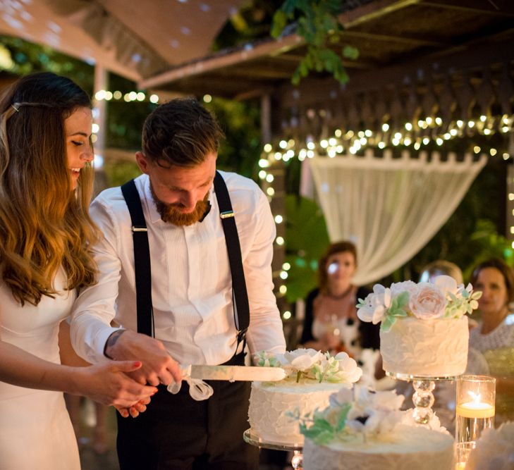 Cutting the Wedding Cake | Bride in Suzanne Neville Wedding Dress & Flower Crown | Groom in Reiss Suit | Outdoor Ibiza Destination Wedding | Gypsy Westwood Photography | Infin8 Film