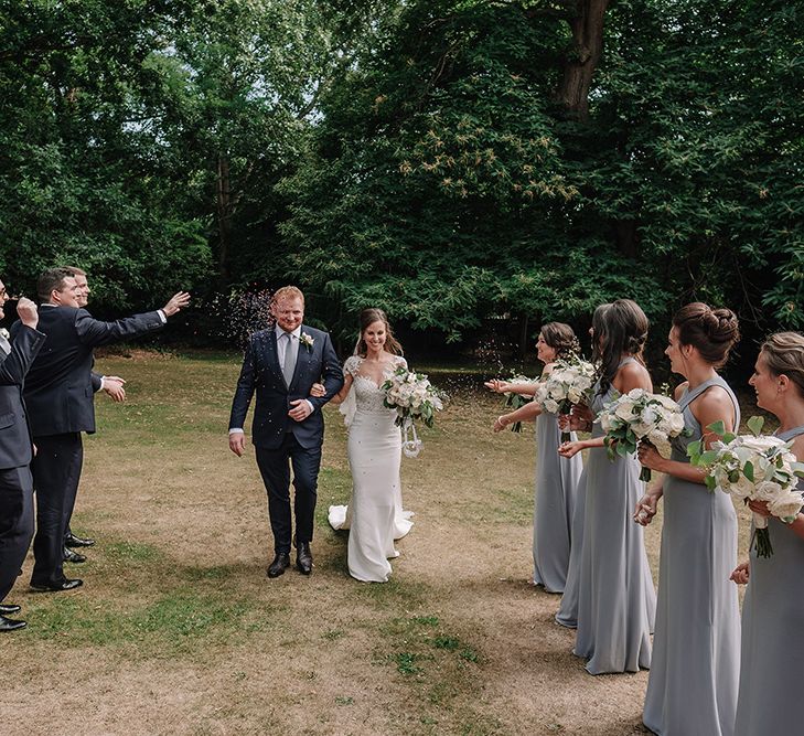 Confetti Exit | Bride in Lace Pronovias Bridal Gown | Groom in Thom Sweeney Suit | White and Silver English Country Garden At Home Marquee Wedding | Jason Mark Harris Photography