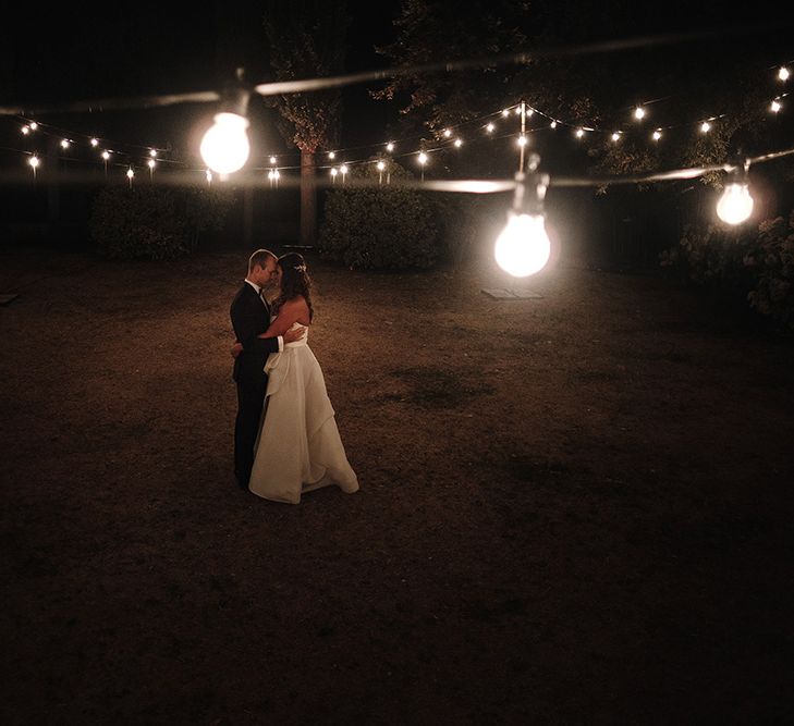 Festoon Lights | Bride in Monique Lhuillier Gown | Groom in Tuxedo | Super Luxe Blush, White & Greenery Destination Wedding at Villa Pitiana, Tuscany, Italy | Jason Mark Harris Photography | Angelo La Torre Film