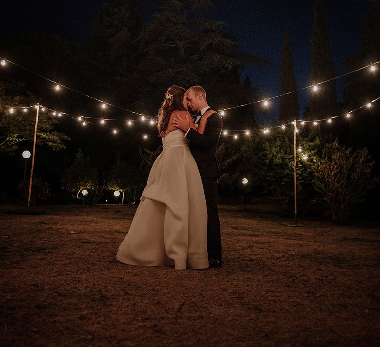 Festoon Lights | Bride in Monique Lhuillier Gown | Groom in Tuxedo | Super Luxe Blush, White & Greenery Destination Wedding at Villa Pitiana, Tuscany, Italy | Jason Mark Harris Photography | Angelo La Torre Film