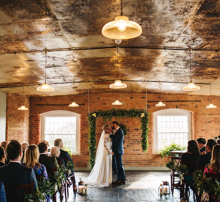 Bride in Charlie Brear Torum Dress & Adrianna Lace Jacket | Industrial Wedding Ceremony at The West Mill | Greenery Flower Arch | S6 Photography