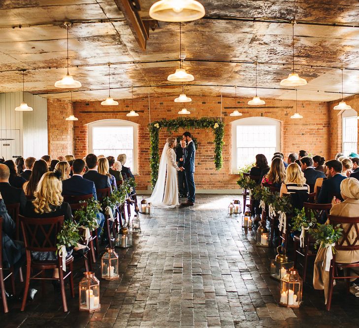 Bride in Charlie Brear Torum Dress & Adrianna Lace Jacket | Industrial Wedding Ceremony at The West Mill | Greenery Flower Arch | S6 Photography