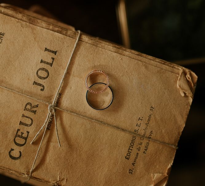 Wedding rings in dark wedding photo propped on old book