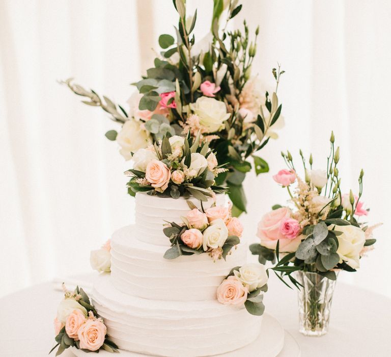 White Wedding Cake Covered In Flowers