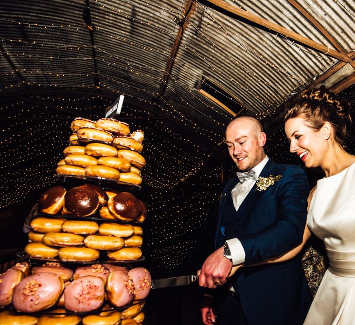 Bride & Groom Cutting the Krispy Kreme Doughnut Tower Wedding Cake | Michelle Wood Photography