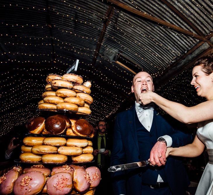 Bride & Groom Cutting the Krispy Kreme Doughnut Tower Wedding Cake | Michelle Wood Photography