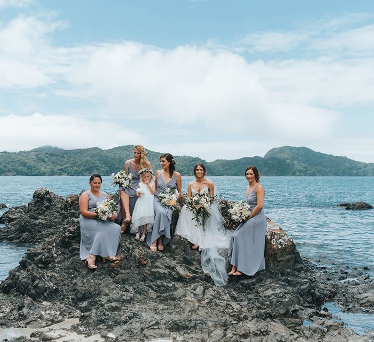 Bridal Party | Bride in Estelle Sally Eagle Gown | Bridesmaids in Powder Blue Evolution Clothing Dresses | Outdoor Coastal Wedding at Ohawini Bay in New Zealand with Natural Garden Party Reception | Miss Gen Photography