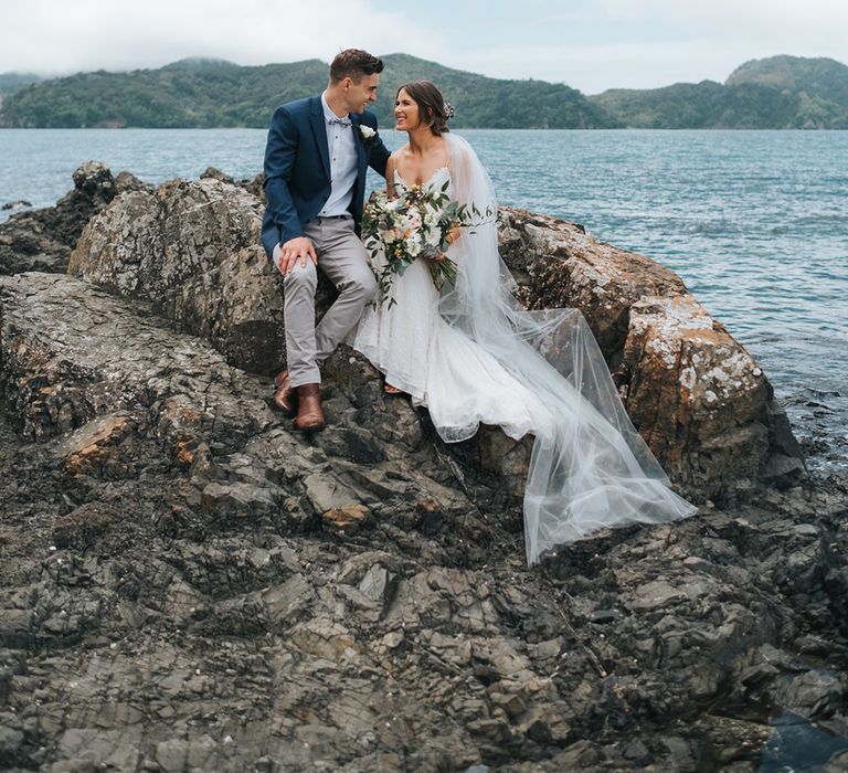 Bride in Estelle Sally Eagle Gown | Groom in Chinos & Blazer | Outdoor Coastal Wedding at Ohawini Bay in New Zealand with Natural Garden Party Reception | Miss Gen Photography