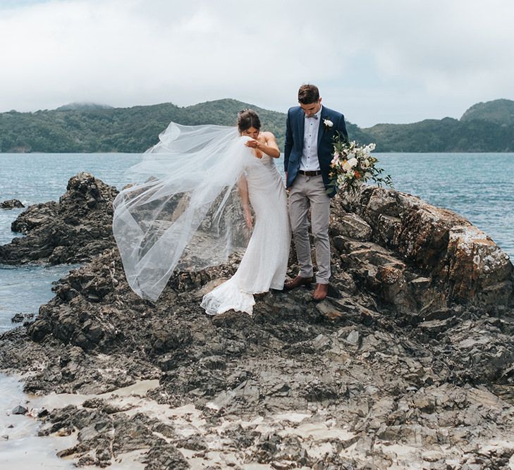 Bride in Estelle Sally Eagle Gown | Groom in Chinos & Blazer | Outdoor Coastal Wedding at Ohawini Bay in New Zealand with Natural Garden Party Reception | Miss Gen Photography