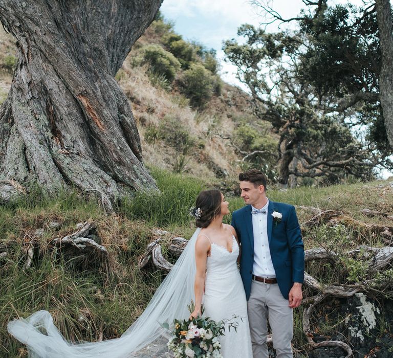 Bride in Estelle Sally Eagle Gown | Groom in Grey Chinos & Navy Blazer | Outdoor Coastal Wedding at Ohawini Bay in New Zealand with Natural Garden Party Reception | Miss Gen Photography