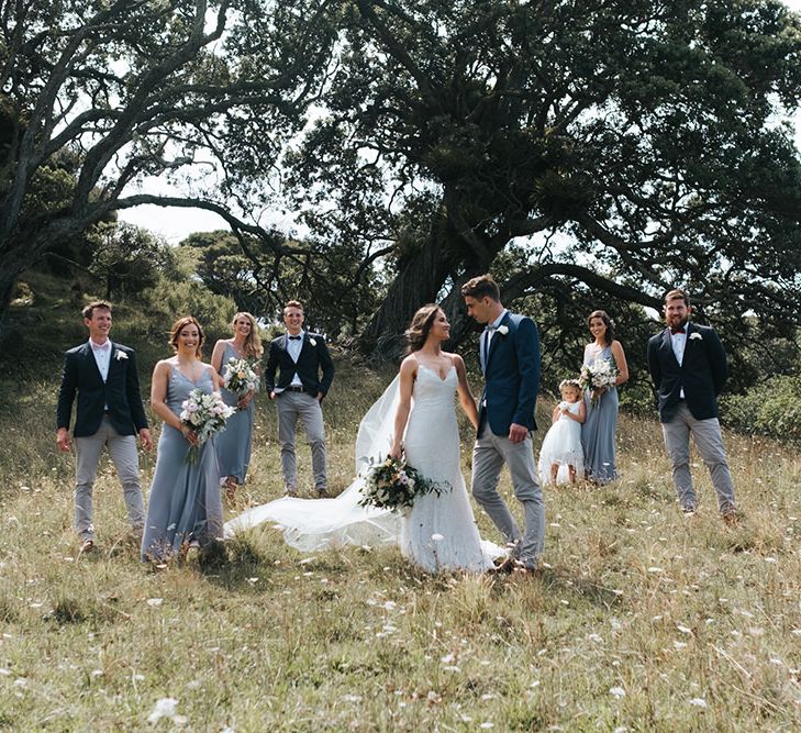 Wedding Party | Bride in Estelle Sally Eagle Gown | Bridesmaids in Powder Blue Evolution Clothing Dresses | Groomsmen in Grey Chinos & Navy Blazers | Outdoor Coastal Wedding at Ohawini Bay in New Zealand with Natural Garden Party Reception | Miss Gen Photography