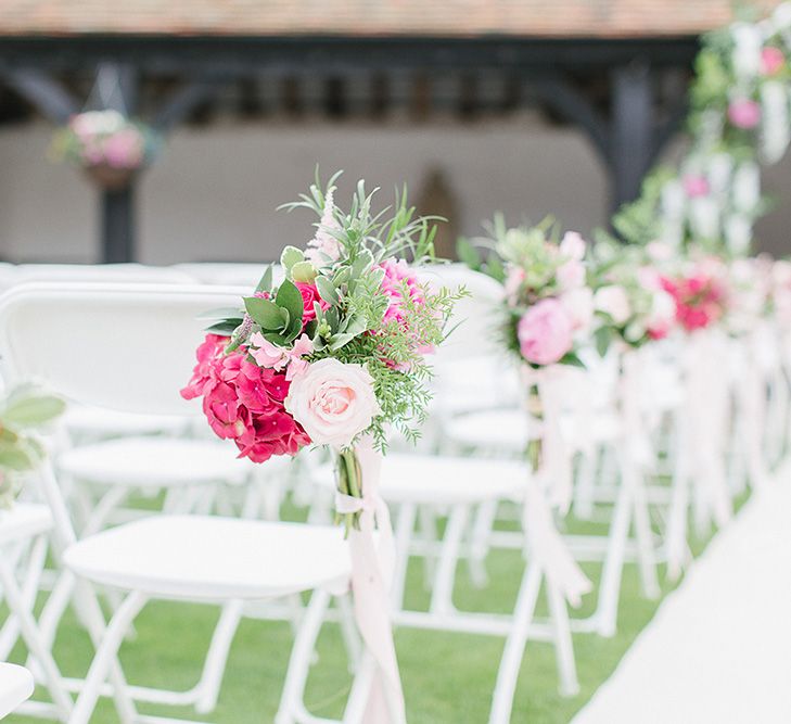 Outdoor Wedding Ceremony With White Chairs & Pink Floral Chairbacks