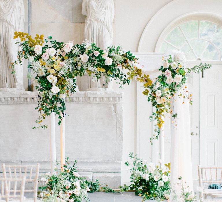 White and green floral arch in light and airy ceremony room