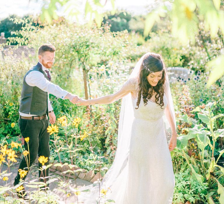 Bride leads groom by the hand through botanical glasshouse