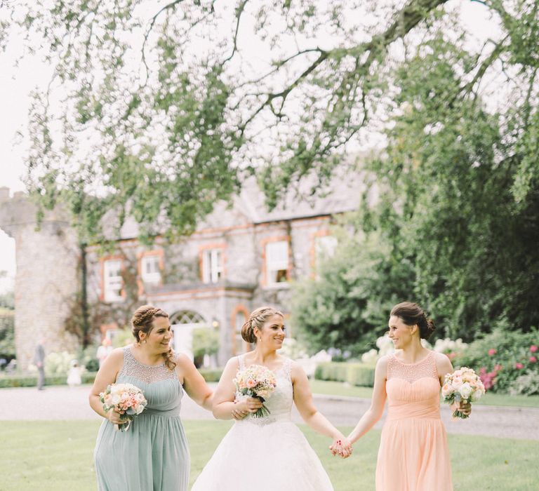 Bride in Modeca Wedding Dress & Bridesmaids in Pastel Peach & Green Gowns