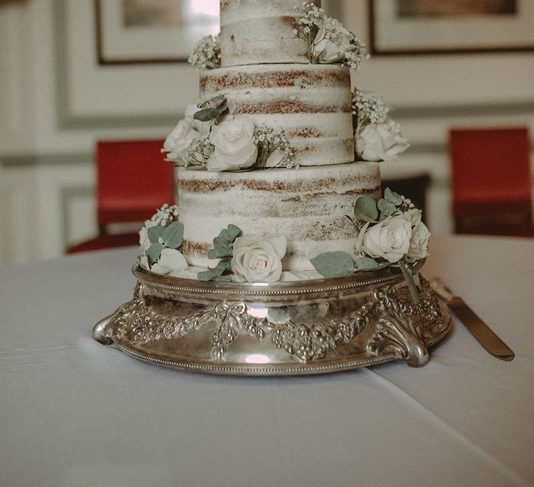 White Semi Naked Wedding Cake On Silver Cake Stand // Elegant White Wedding In Somerset With Bride In Lace Long Sleeved Gown With Open Back And Loose Braid With Hair Vine Images From Carla Blain Photography