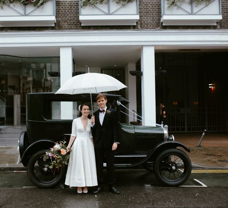 Elegant Bride in Delphine Manivet Prospere Wedding Dress & Groom in Velvet Jacket beside a Vintage Wedding Car