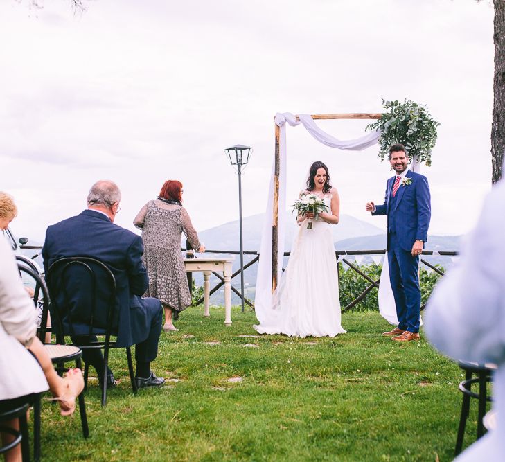 Outdoor Wedding Ceremony | Bride in Naomi Neoh | Groom in French Connection Suit