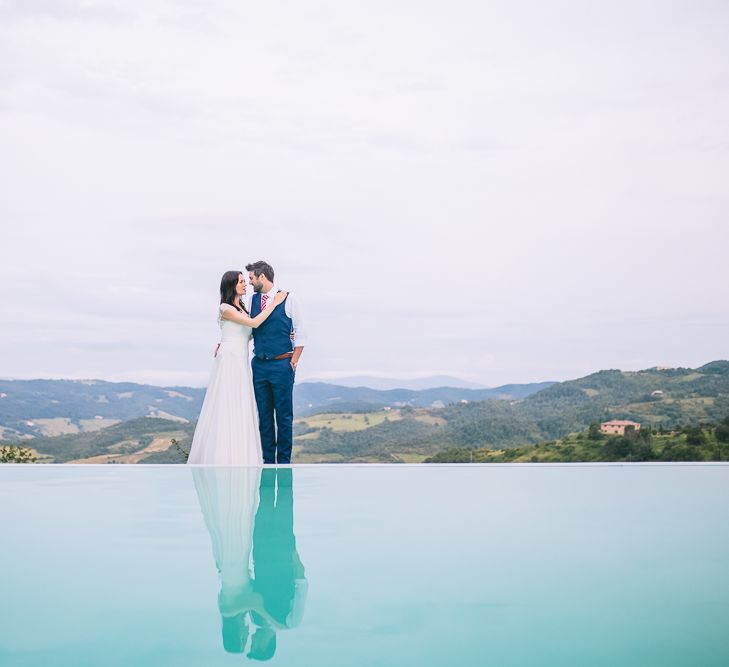 Bride in Naomi Neoh Gown & Groom in French Connection Suit near Pool