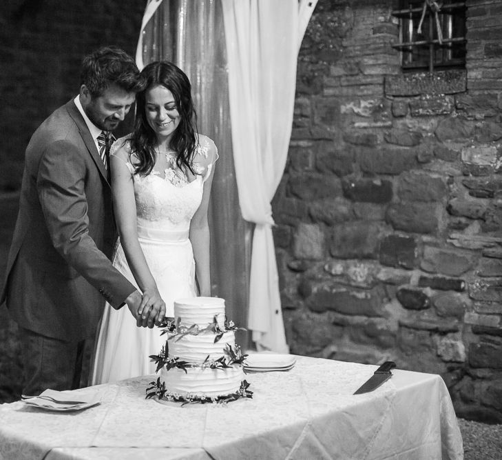 Bride Naomi Neoh Gown & Groom in French Connection Suit Cutting The Wedding Cake