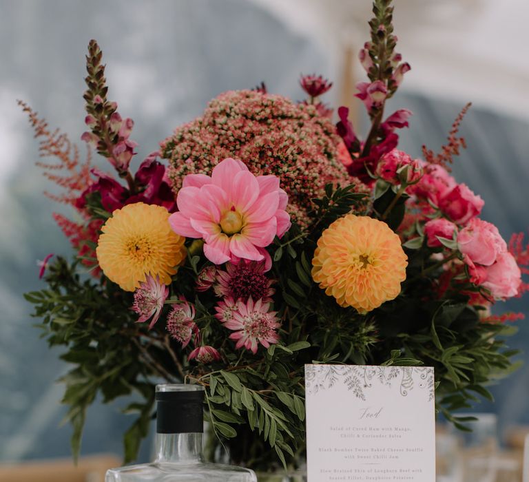 Rustic Centrepieces with Coral Flowers & Gin Bottles | Rural Wedding in a Sailcloth Tent on Stanford Hall Estate, Northamptonshire | Rebecca Goddard Photography