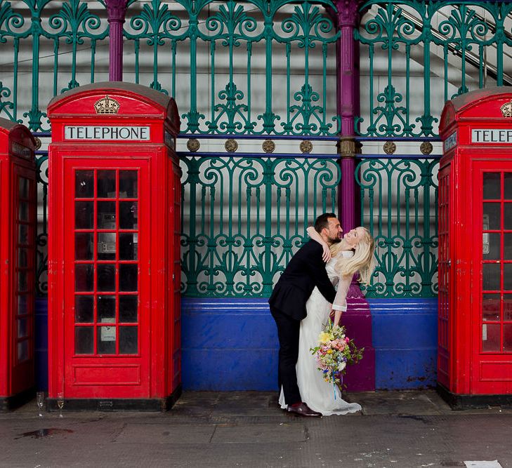 Bride in Charlie Brear Wedding Dress & Groom in Paul Smith Suit next to Red Telephone Boxes