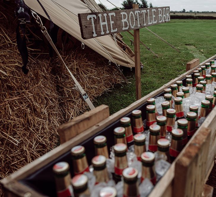 Wooden Trough Bottle Bar | Rustic At Home Tipi Reception with Blush Colour Scheme | Jason Mark Harris Photography | Harris Films