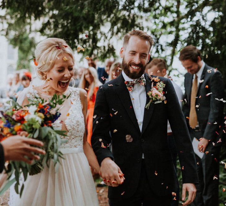 Confetti Exit | Bride in Lace & Tulle Gown | Groom in Black Suit & Liberty Print Bow Tie | Colourful DIY Barn Wedding at The Manor Barn, Cambridge | Meghan Lorna Photography