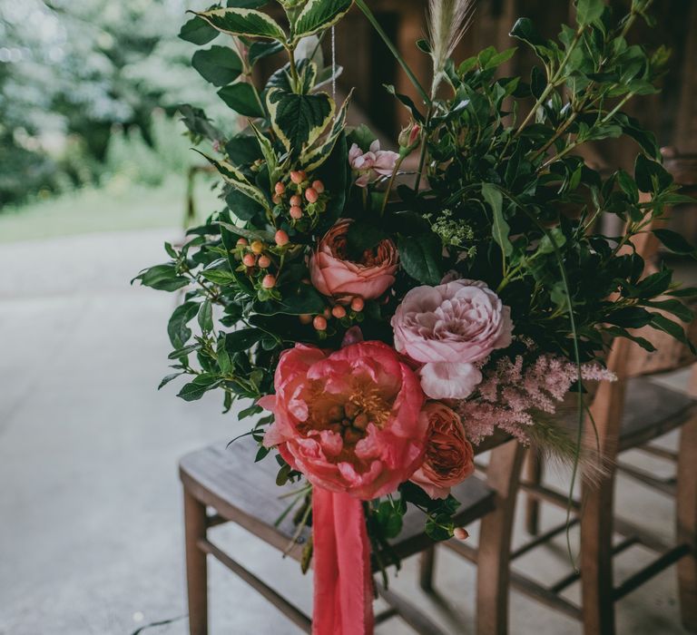 Coral Peony Chair Back Decor | Coral Wedding Cake with Peony Decor | Bride in Anna Campbell Gown from Coco & Kate Boutique | Groom in Next Wool Suit | Rustic Barn Pink Summer Wedding at Nancarrow Farm in Cornwall | Ross Talling Photography