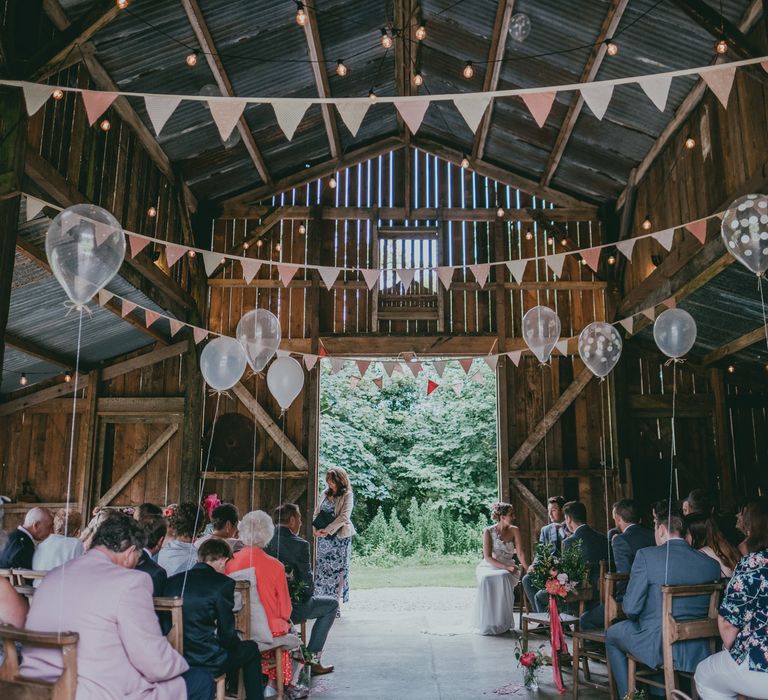 Wedding Ceremony | Liberty Print bunting | Balloon Decor | Bride in Anna Campbell Gown | Groom in Grey Wool Suit | Coral Wedding Cake with Peony Decor | Bride in Anna Campbell Gown from Coco & Kate Boutique | Groom in Next Wool Suit | Rustic Barn Pink Summer Wedding at Nancarrow Farm in Cornwall | Ross Talling Photography