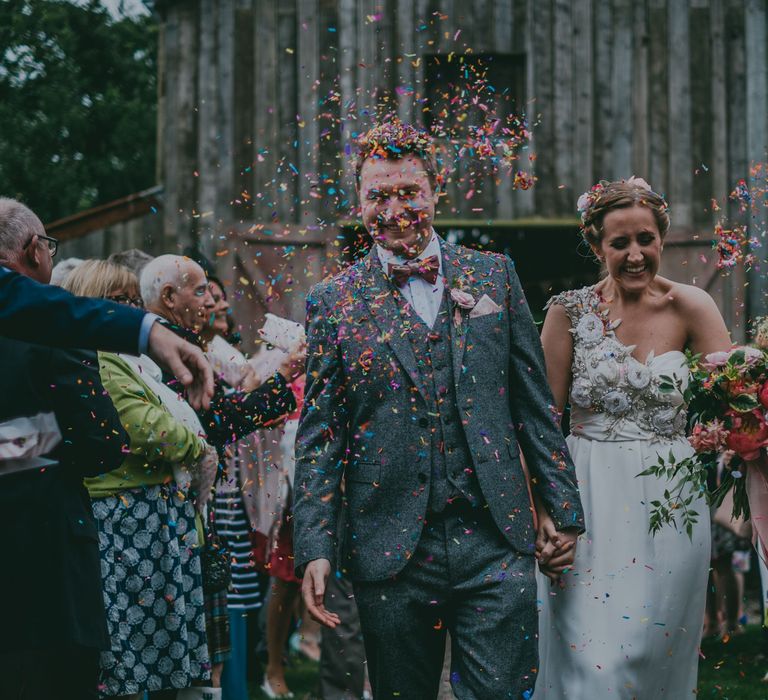 Confetti Moment | Bride in Anna Campbell Gown | Groom in Grey Wool Suit | Coral Wedding Cake with Peony Decor | Bride in Anna Campbell Gown from Coco & Kate Boutique | Groom in Next Wool Suit | Rustic Barn Pink Summer Wedding at Nancarrow Farm in Cornwall | Ross Talling Photography