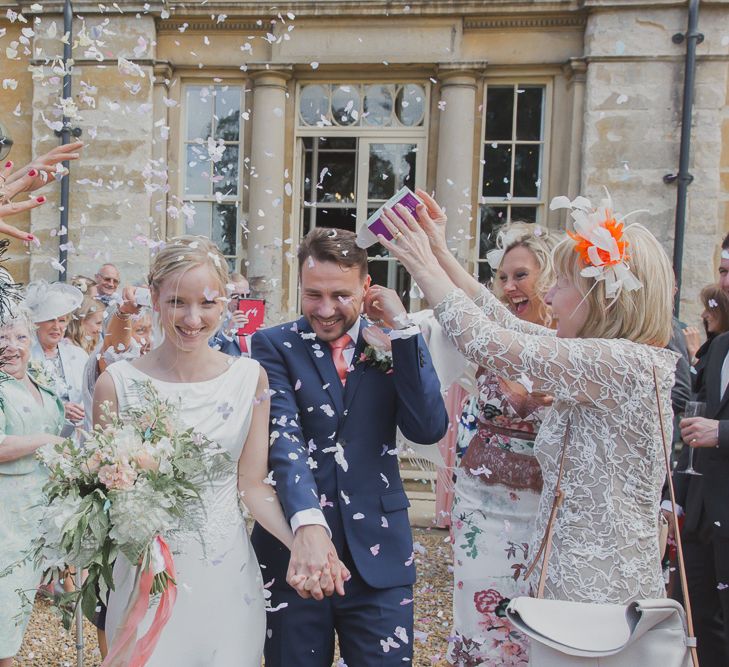 Confetti Moment | Bride in Justin Alexander Gown | Groom in Moss Bros Suit | Outdoor Peach Wedding at Courteenhall House in Northamptonshire Planned by Your Story Events | Ferri Photography