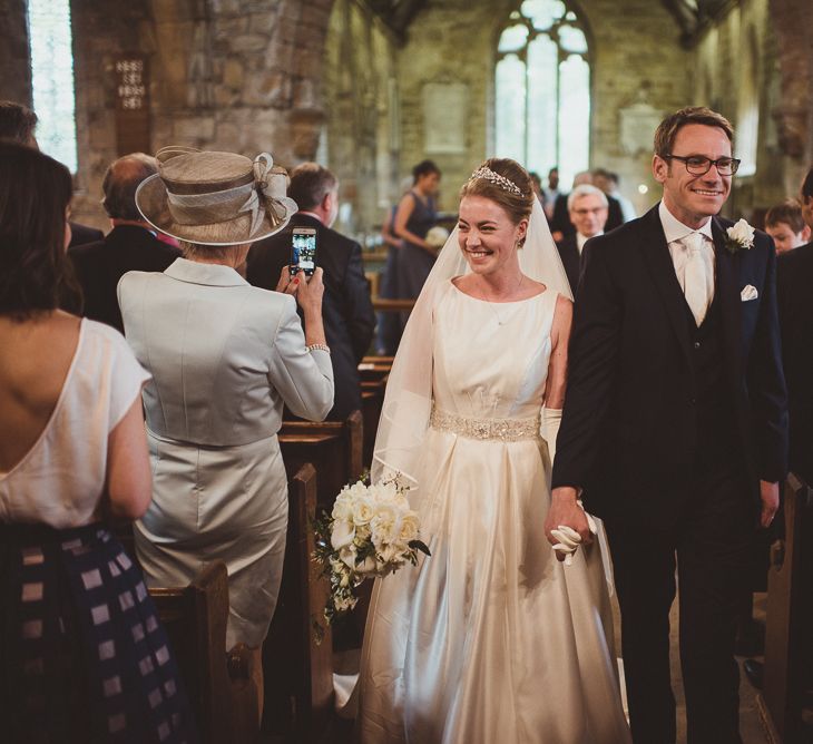 Bride in Tom Flowers Dress, Long Satin Gloves & Ivory & Co. Headdress and Groom in Moss Bros Suit at Church Wedding Ceremony