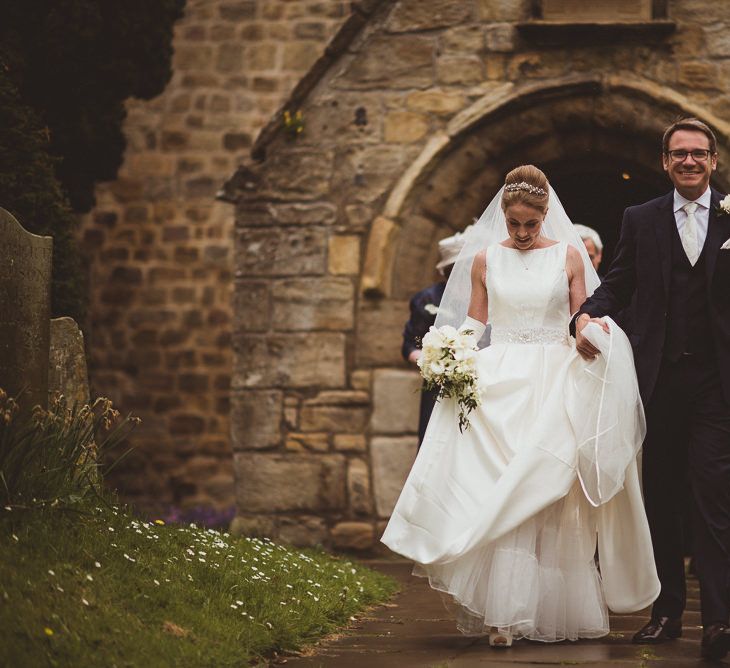 Bride in Tom Flowers Dress, Long Satin Gloves & Ivory & Co. Headdress and Groom in Moss Bros Suit