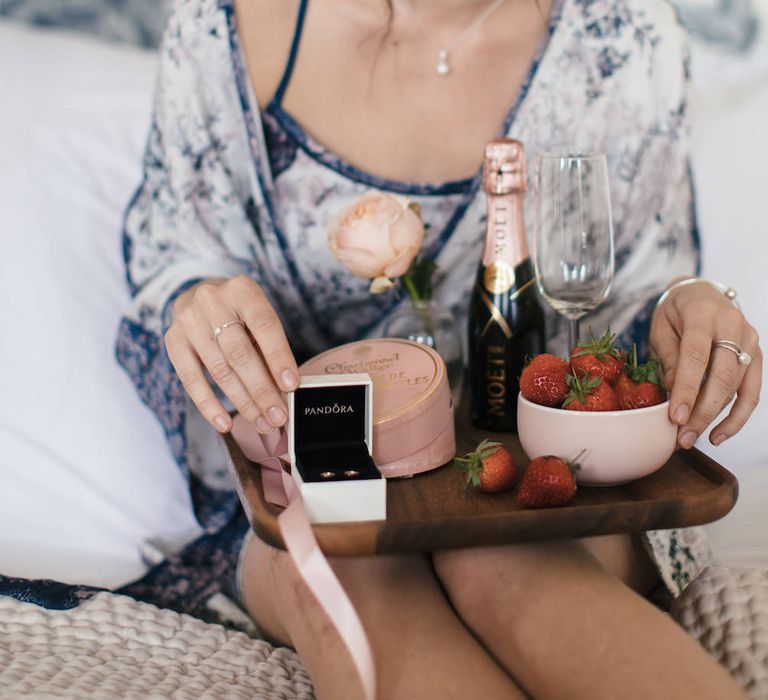 Bridesmaid in floral chemise and breakfast tray with PANDORA rose gold earrings