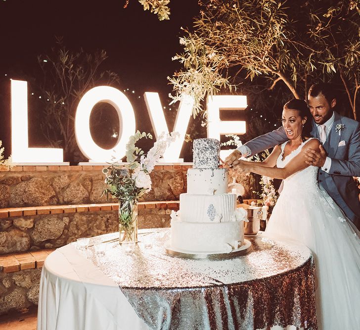 Bride & Groom Cutting the Cake with Giant LOVE Light Up Letters Backdrop