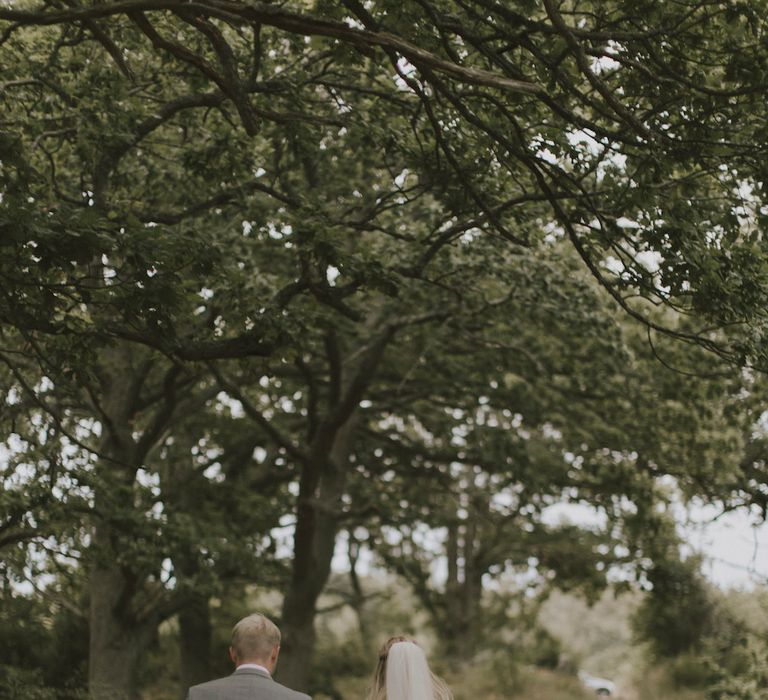 Bride in By Malina Bridal Gown & Groom in Grey Tiger of Sweden Suit