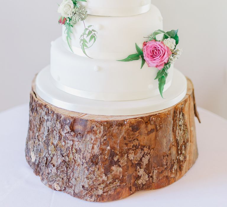 Traditional White Wedding Cake with Pink Flowers on a Tree Stump Cake Stand