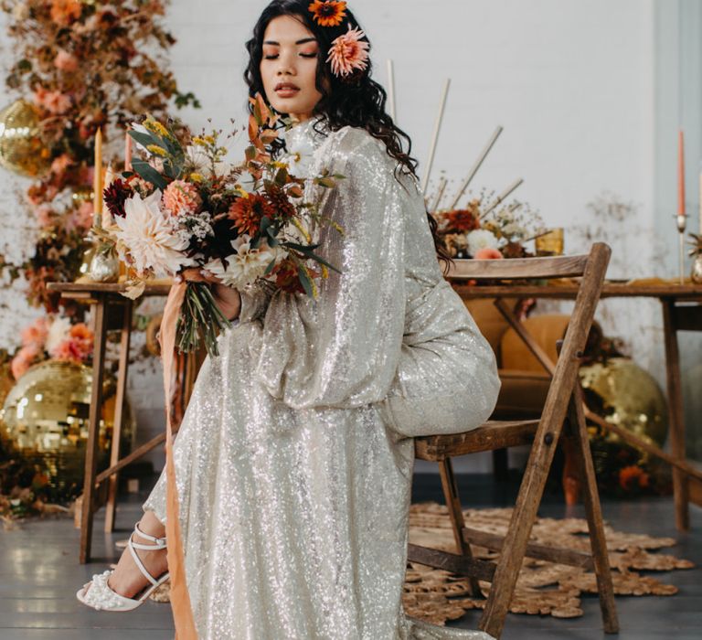 Bride in silver sequin wedding dress holding an autumnal bouquet for 70s Disco theme