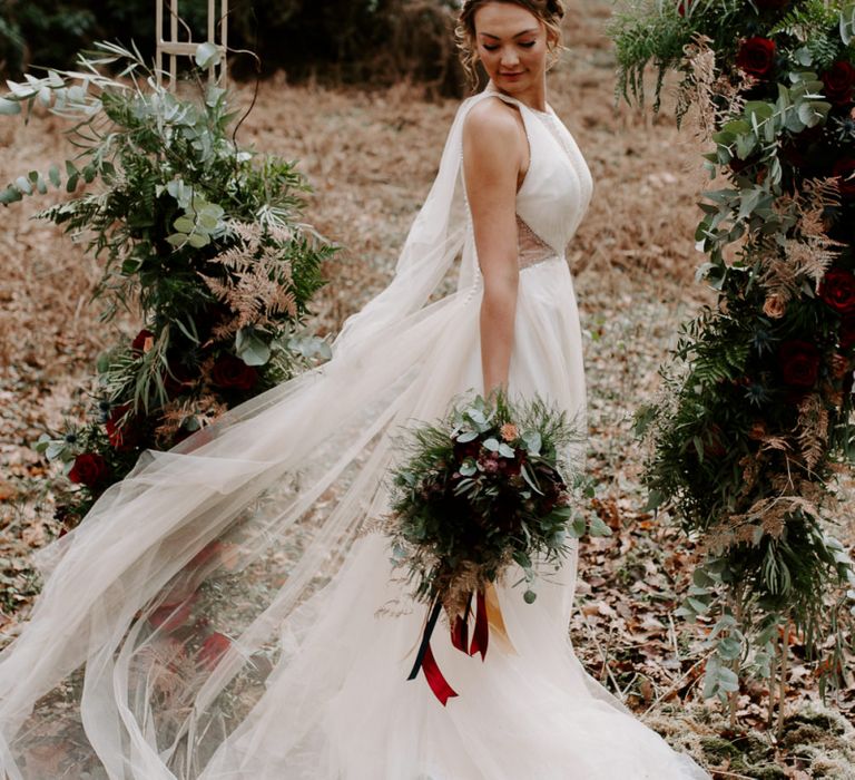 Boho Bride in Chiffon Wedding Dress with Veil and Red Bouquet.