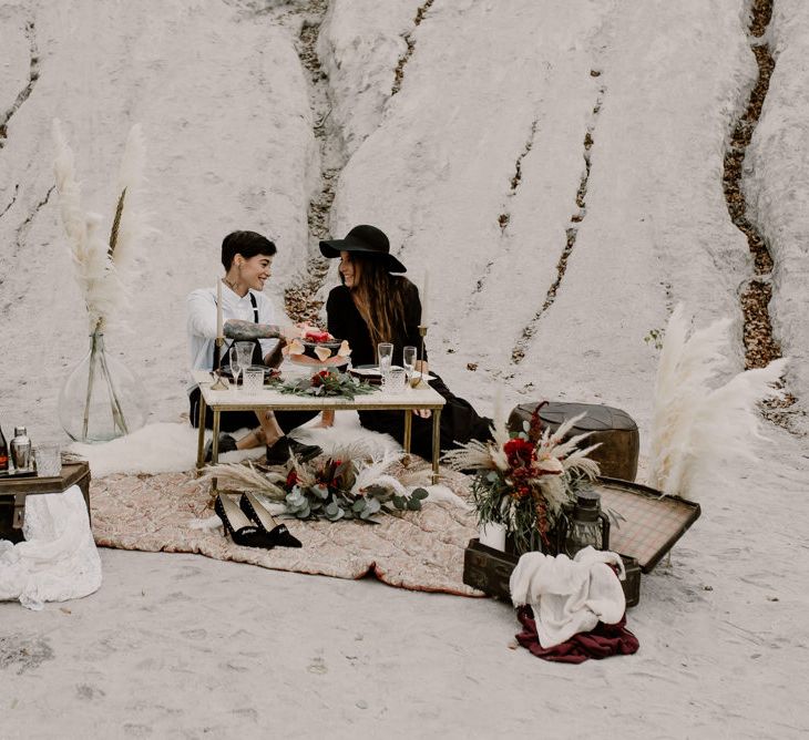 Sweetheart Table with Vintage Wedding Decor &amp; Pampas Grass Floral Arrangements | Bride in Portez Vos Idées Black Wedding Dress | Pampas Grass, Eucalyptus &amp; Red Rose Wedding Bouquet | Bride in Black Trousers, White Shirt &amp; Braces | Wild Same Sex Couple Wedding Inspiration Shoot | Anne Letournel Photography