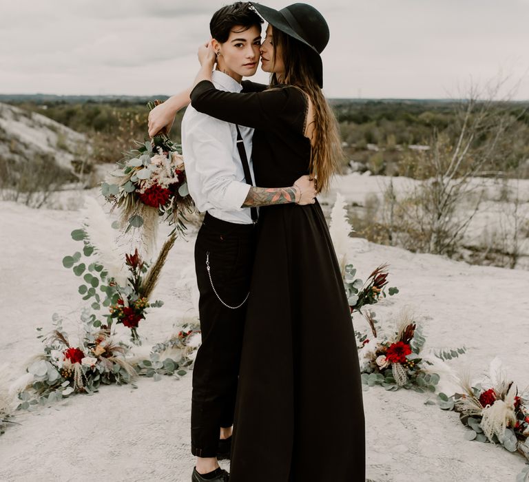 Two Brides | Bride in Portez Vos Idées Black Wedding Dress | Horseshoe Pampas Grass, Eucalyptus &amp; Red Rose Floral Arrangement | Wild Same Sex Couple Wedding Inspiration Shoot | Anne Letournel Photography